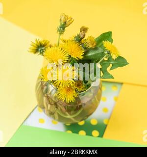 Bouquet de pissenlits jaunes colorés dans vase en verre, fleurs sur fond coloré lumineux, concept de printemps, vacances Banque D'Images