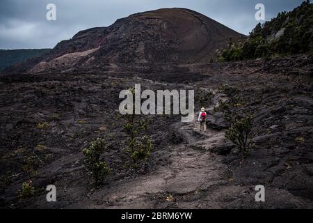 Une femme marche vers pu’u Pua’i ou Gushing Hill, une caractéristique volcanique du parc national des volcans d’Hawaï, Hawai’i, États-Unis Banque D'Images