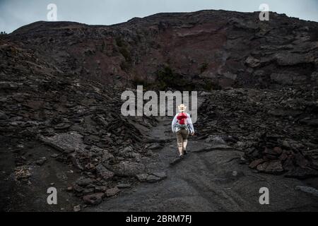 Une femme marche vers pu’u Pua’i ou Gushing Hill, une caractéristique volcanique du parc national des volcans d’Hawaï, Hawai’i, États-Unis Banque D'Images