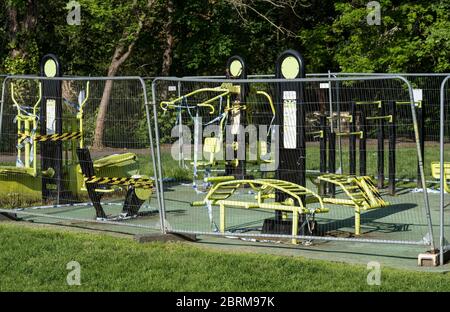 Équipement de gym extérieur dans le parc, enveloppé dans des bandes de danger et de police, puis enroulé derrière des écrans de mesh pendant le confinement pandémique COVID-19. Banque D'Images