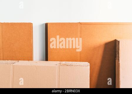 Les cartes empilées sur un mur blanc sont prêtes à former des boîtes pour transporter les articles ménagers. Banque D'Images