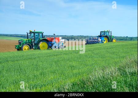 Deux tracteurs semis de récolte sur le champ de grain, ciel bleu Banque D'Images