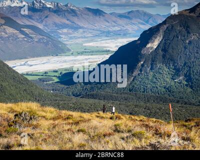 Les trampers descendant vers la route Burn depuis le col de Sugarloaf (1154m), la rivière Dart dans le bg, le parc national du Mont Aspiring, Otago, Nouvelle-Zélande Banque D'Images