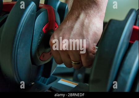 Haltères réglables à la main pour l'entraînement à la maison. Main mâle avec anneau visible. Banque D'Images