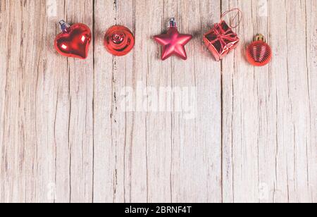 Panneau en bois brun avec ornement de Noël rouge:coeur, cloche, étoile, boîte cadeau et lance, prêt pour le montage de l'affichage de produit. Banque D'Images