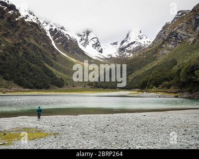 Unique marcheur au lac Mackenzie, avec Emily Pass en arrière-plan, Routeburn Track, parc national Fiordland, Nouvelle-Zélande Banque D'Images