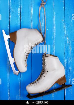 Paire de patins pour femme en cuir blanc figure skating hanging on a blue background Banque D'Images