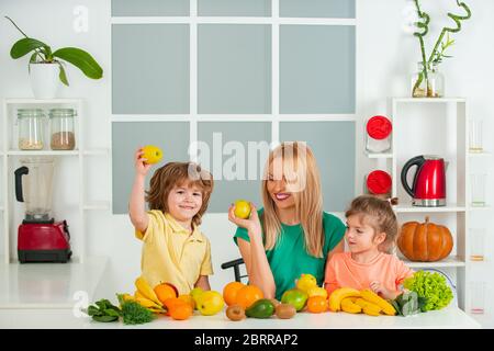 Maman fille et fils préparent un smoothie dans la cuisine. Amusez-vous et jouez avec les légumes. Une alimentation saine et un mode de vie sain pour les enfants. Nutrition végétalienne et a Banque D'Images