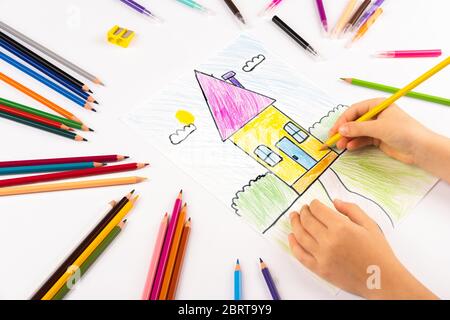 Un enfant dessine une maison. Créativité maison. Image lumineuse sur papier blanc. Banque D'Images