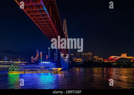 Chongqing, Chine - août 2019 : bateau touristique de luxe naviguant sous le pont lumineux DongShuiMen, traversant le fleuve Yangtze à nig Banque D'Images