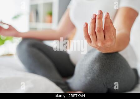 Femme enceinte méditant en étant assise sur le lit Banque D'Images