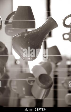 Photographie sépia monochrome des silhouettes d'ustensiles de cuisine. Vase en céramique, tasses à café et tasses à thé sont suspendus sur des cordes Banque D'Images
