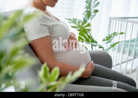 Femme enceinte assise confortablement dans le fauteuil Banque D'Images