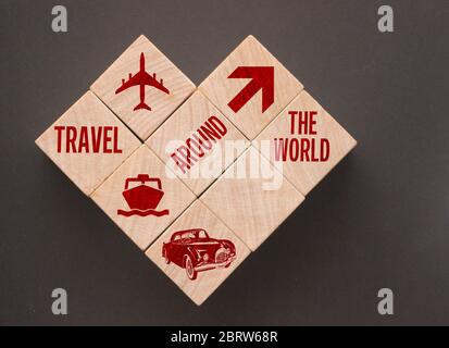 Forme de coeur formée de cubes en bois avec des icônes de voyage sur fond noir. Concept de voyage Banque D'Images