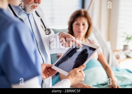 Médecin senior examinant une patiente à l'hôpital, vérifiant la radiographie. Banque D'Images
