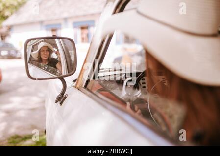 Une belle jeune femme avec un chapeau de paille conduit un vieux camion blanc. La vie dans un village Banque D'Images