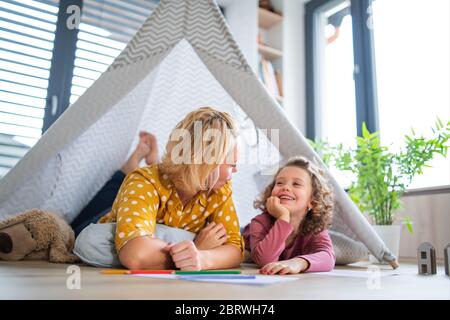 Une petite fille mignonne avec une mère à l'intérieur à la maison, jouant. Banque D'Images