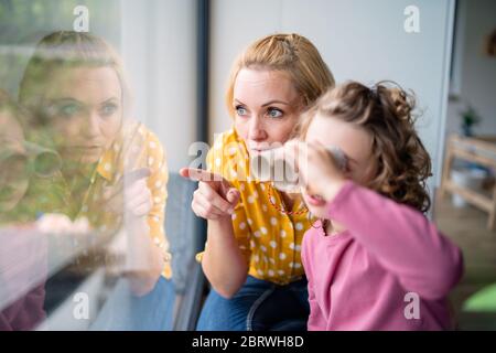 Une petite fille mignonne avec une mère à l'intérieur à la maison, jouant. Banque D'Images