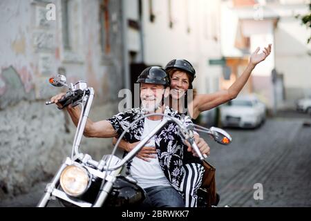 Un couple de personnes âgées gaies avec moto en ville. Banque D'Images