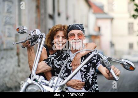 Un couple de personnes âgées gaies avec moto en ville. Banque D'Images