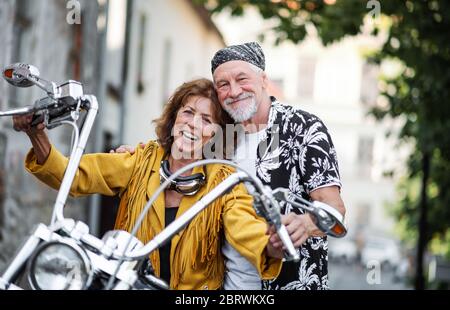 Un couple de personnes âgées gaies avec moto en ville. Banque D'Images