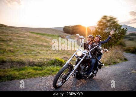 Couple de voyageurs âgés joyeux avec moto à la campagne. Banque D'Images