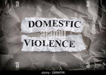 Violence domestique. Morceaux de papier déchirés avec les mots violence domestique écrits sur eux sur fond de papier froissé. Image de concept. Gros plan. Banque D'Images