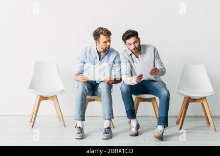 Les candidats avec ordinateur portable qui regarde le CV en attendant l'entrevue d'emploi au bureau Banque D'Images