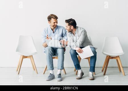 Souriant les candidats avec un ordinateur portable et de reprendre l'attente de l'entrevue d'emploi au bureau Banque D'Images