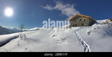 chalet alpin traditionnel au sommet de la montagne enneigée sous le soleil levant dans le ciel Banque D'Images