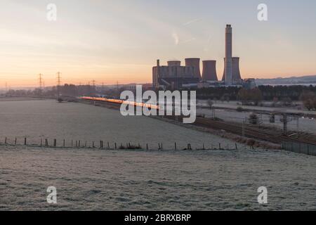 Un Londres à Manchester Piccadilly - Virgin Trains Pendolino côte ouest passe Rugeley power station (au sud de Stafford) comme le soleil se lève Banque D'Images