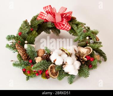 Couronne de Noël avec perles brillantes rouges, fleurs de coton et tranches d'oranges séchées Banque D'Images