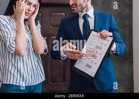 Collecteur pointant vers des documents avec le lettrage de forclusion près de la femme stressée dans la chambre Banque D'Images