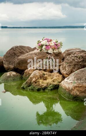 bouquet de mariage de roses pourpres et blanches sur des pierres Banque D'Images