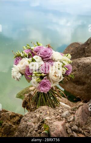 bouquet de mariage de roses pourpres et blanches sur des pierres Banque D'Images