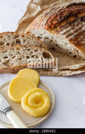 Pain frais de levain de pain avec tranches coupées et un plat de beurre frais Banque D'Images