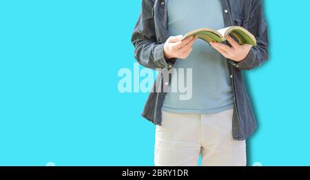 Photo d'un jeune homme isolé sur fond de mur bleu tenant le livre de lecture. Avec espace libre. Banque D'Images