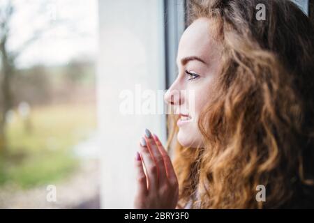 Portrait en gros plan de la jeune femme debout près de la fenêtre à l'intérieur à la maison. Banque D'Images