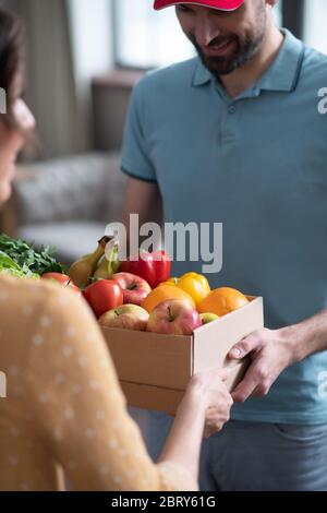 Une cliente aux cheveux foncés reçoit des produits d'épicerie du courrier masculin Banque D'Images