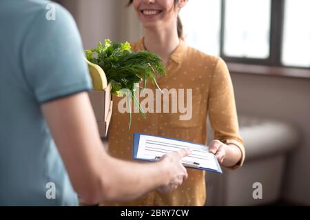 Le client aux cheveux foncés reçoit les produits d'épicerie livrés par le coursier Banque D'Images