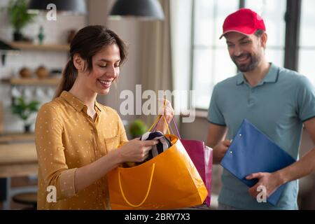 Client aux cheveux sombres qui ouvre le sac et qui sourit Banque D'Images