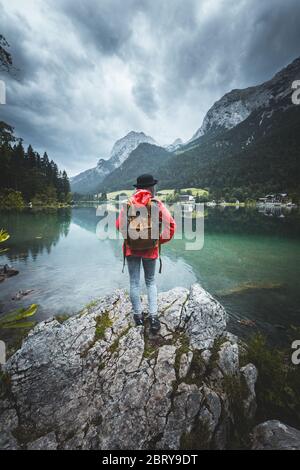 Concept de l'homme et de la nature. Une touriste féminine profite de la vue du matin depuis la rive, regarde les montagnes et le lac, étant seul voyageur, regardant la beauté, porte Banque D'Images