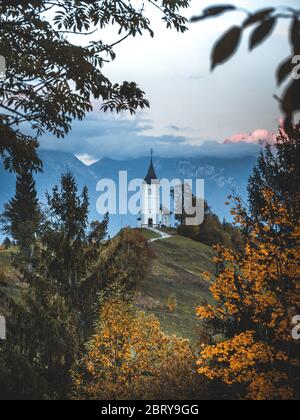 Église Jamnik St Primus et Felicien au coucher du soleil, Slovénie. Paysage incroyable avec chemin à pied de l'église sur le côté de la colline, ciel nuageux spectaculaire, bac de voyage Banque D'Images