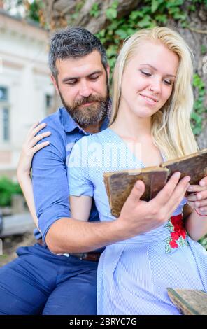 Concept de date et d'amour. Couple dans amour assis et câlins extérieur, fond de nature. Fille avec le visage heureux automne dans l'amour avec l'homme barbu, couple lit des poèmes. Couple romantique tient un vieux livre avec des poèmes. Banque D'Images