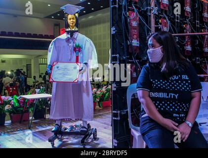 Manille. 22 mai 2020. Un enseignant regarde l'image d'un étudiant affichée sur une tablette attachée à un robot lors d'une « cyber-remise de diplômes » dans une école secondaire à Manille, aux Philippines, le 22 mai 2020. Quelque 179 étudiants ont participé à la cérémonie de « cyber-remise des diplômes » au moyen de robots et de médias sociaux, l'interdiction des rassemblements de masse étant toujours mise en œuvre aux Philippines pour empêcher la propagation de la COVID-19. Crédit: Rouelle Umali/Xinhua/Alay Live News Banque D'Images