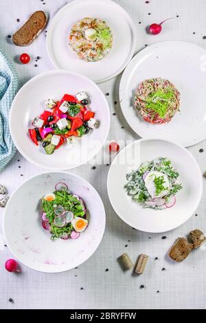 Différentes salades sur une table en bois, vue sur le dessus. Salade de légumes, salade au saumon fumé, viande cuite avec légumes. Arrière-plan de la nourriture, vue du dessus Banque D'Images