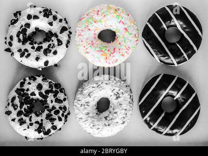 Image plate de six beignets en anneau avec glaçure blanche et des centaines et milliers de couleurs, chocolat et rayures et glaçure blanche avec biscuits noirs, bla Banque D'Images