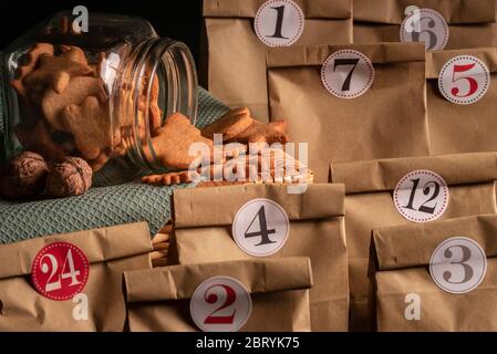 Pot en verre renversé avec plein d'épices biscuits de Noël entouré de sacs de papier numérotés, un selfmade calendrier de l'avent. Banque D'Images