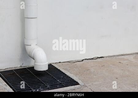 Les tuyaux d'eau de pluie continuent de descendre du haut et sont déchargés à l'égout. Banque D'Images