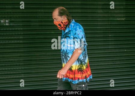 WIMBLEDON LONDRES, ROYAUME-UNI. 22 mai 2020. Un piéton portant un revêtement de visage pour se protéger contre les infections de Covid-19 marche vêtu d'un maillot tropical hawaïen coloré dans le centre-ville de Wimbledon. Crédit : amer ghazzal/Alay Live News Banque D'Images